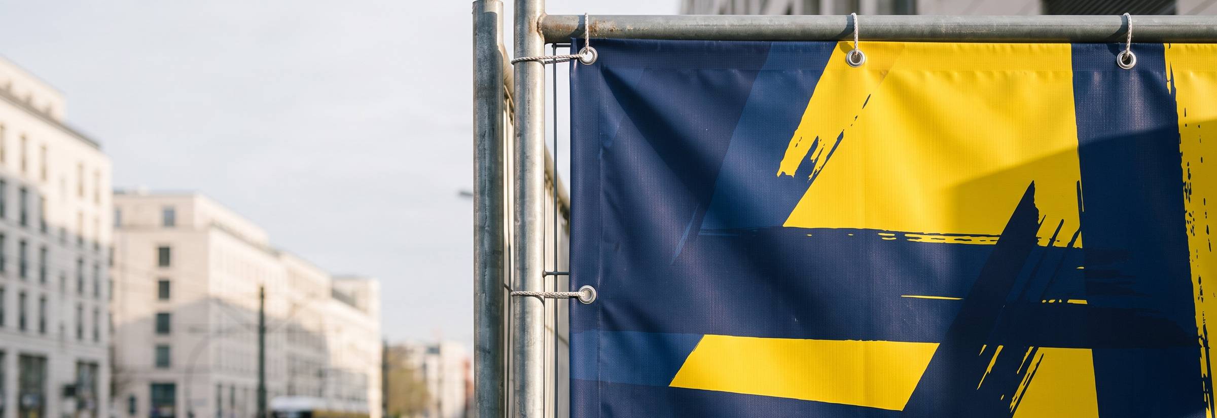 Bedrucktes PVC-Banner mit Ösen an einem Bauzaun